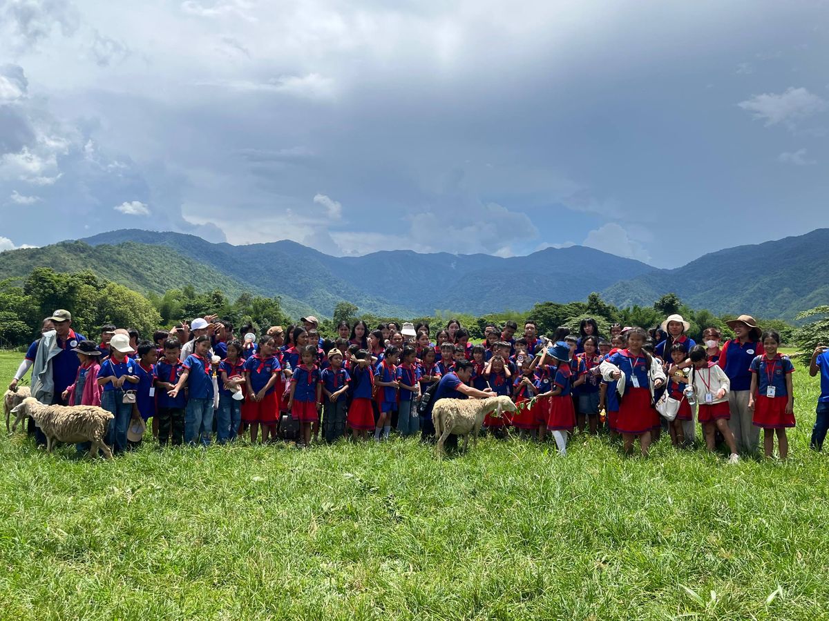 Students on a farm field trip with sheep and mountain views